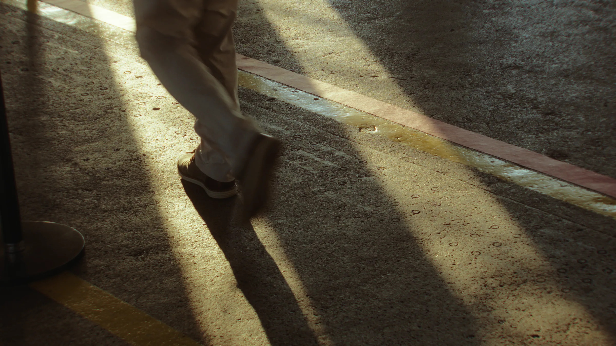 Motion-blurred close-up of feet walking across a sunbeam-streaked floor