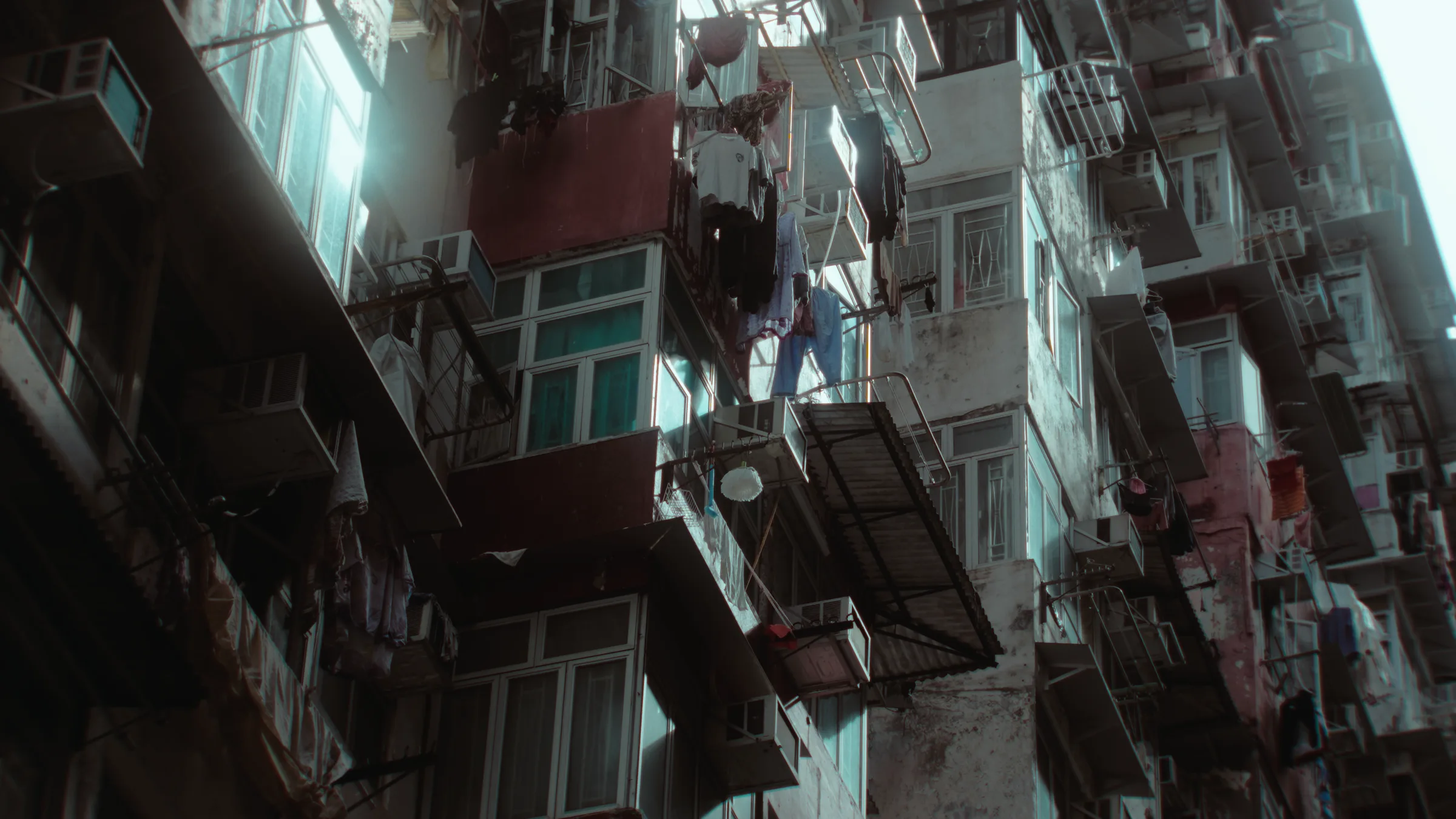Low angle looking up at a Hong Kong tenement block, laundry and air conditioning units hanging from every balcony